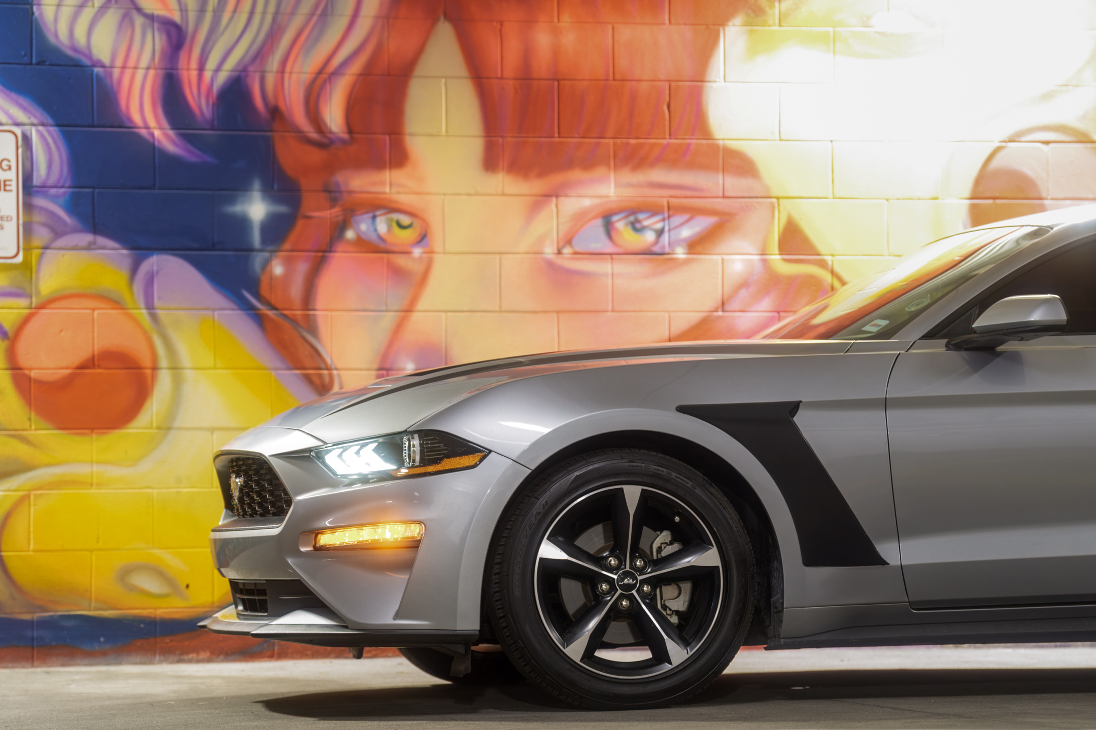 Silver Ford Mustang in front of an urban mural